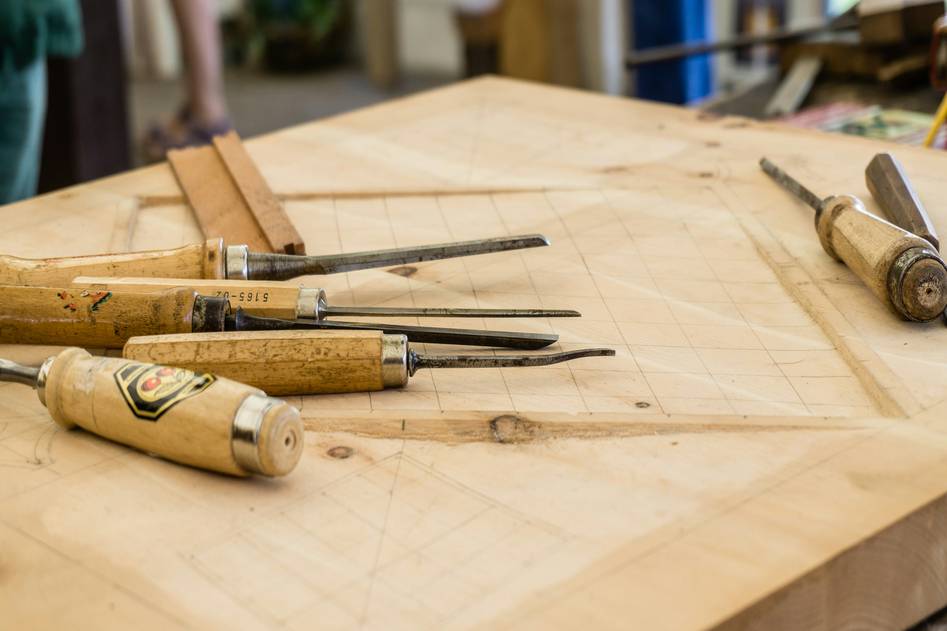 Beginner woodworker using hand saw on pine board in bright workshop